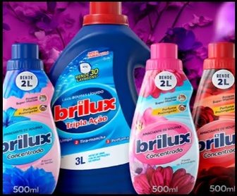 Imagem promocional da campanha Brilux que apresenta um kit de limpeza exclusivo, com quatro frascos de amaciantes concentrados em embalagens vibrantes e um frasco do Lava Roupas Brilux Tradicional, dispostos sobre uma superfície moderna, simbolizando a transformação na rotina doméstica.