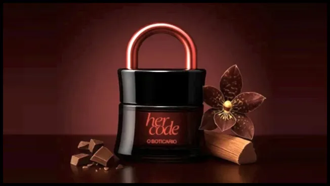 Imagem promocional do perfume Her Code Clímax de O Boticário, em formato exclusivo de cadeado, ilustrada com pedaços de chocolate e uma flor, destacando os elementos olfativos marcantes da fragrância.