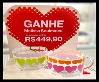 imagem promocional da Melissa com duas xícaras exclusivas da coleção Soulmates em frente a um cartaz com coração vermelho e oferta especial para o Dia dos Namorados 2025